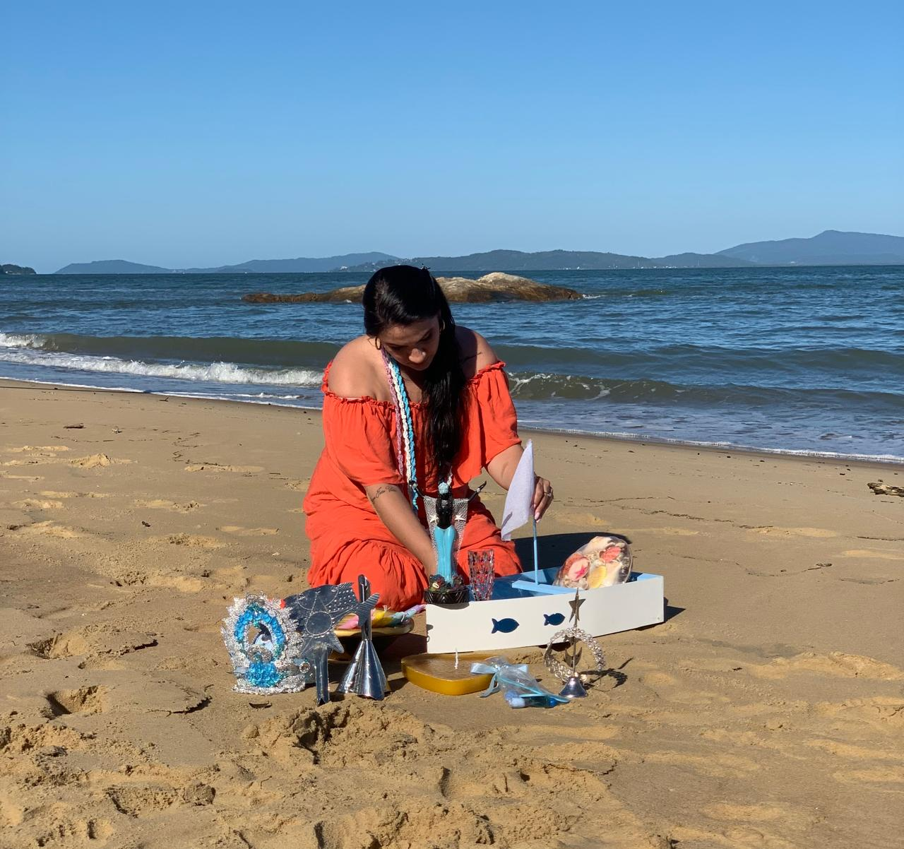 Profissional preparando oferenda na praia diante do mar