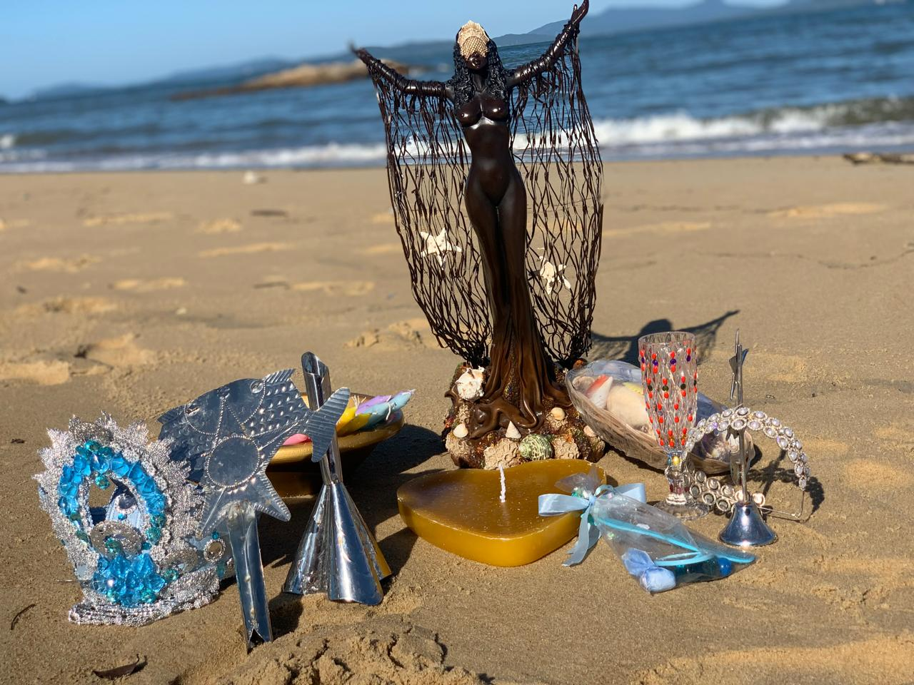 Oferenda à beira-mar com imagem de Iemanjá, velas e adornos