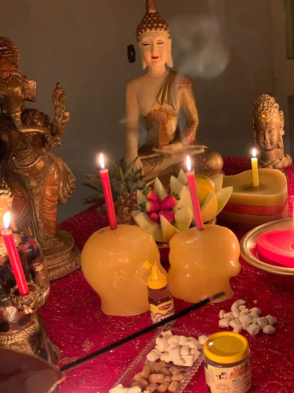 Altar iluminado com velas, frutas e imagens sagradas preparado para o trabalho